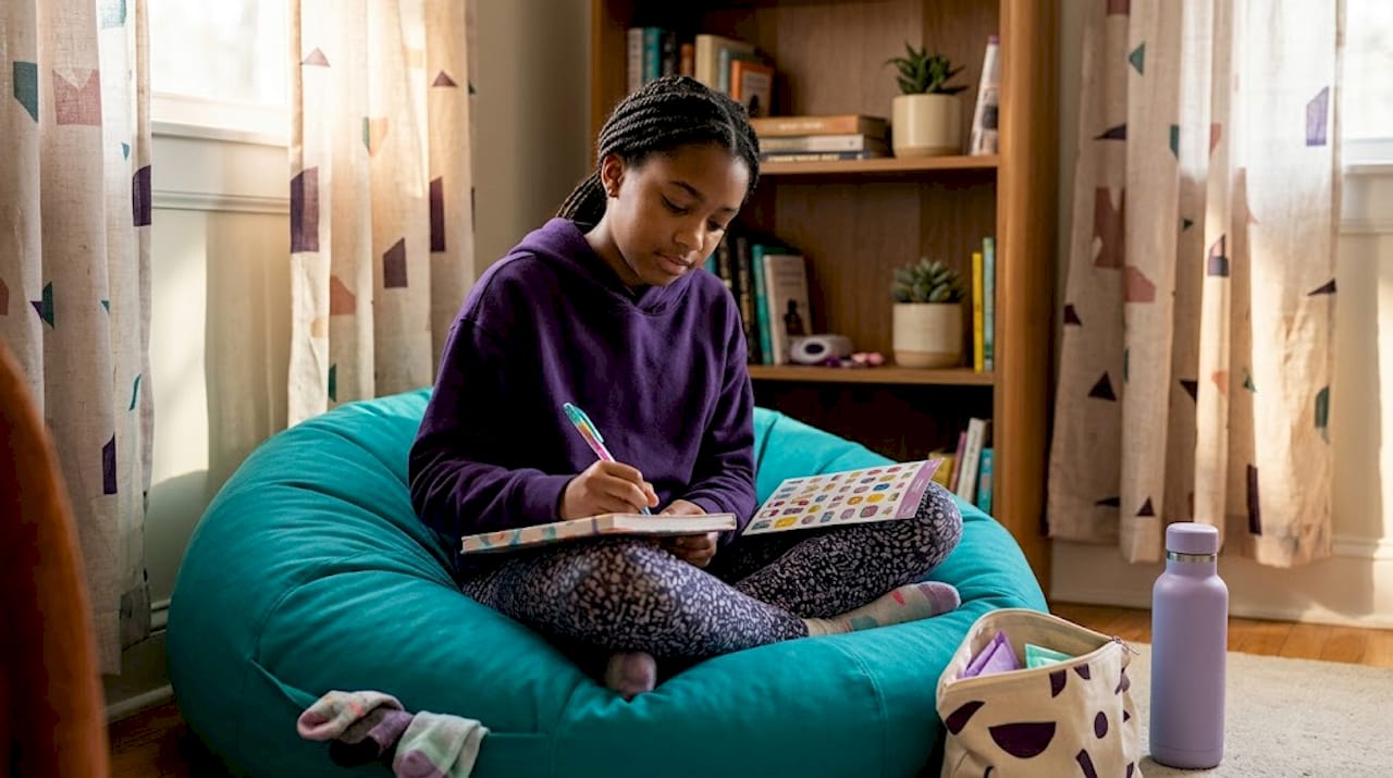 Pre-teen girl journaling self-care routine in bedroom
