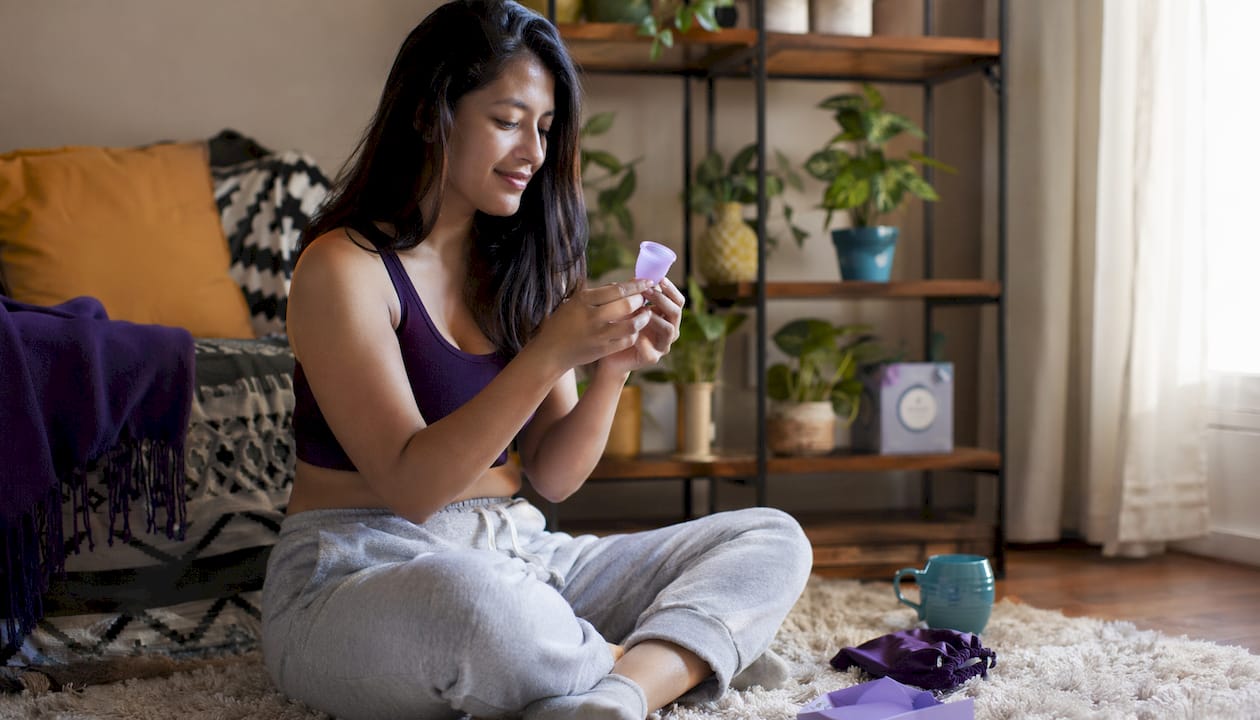 Woman examining menstrual cup at kitchen table