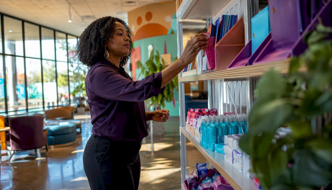 Librarian arranging menstrual health supplies on shelf