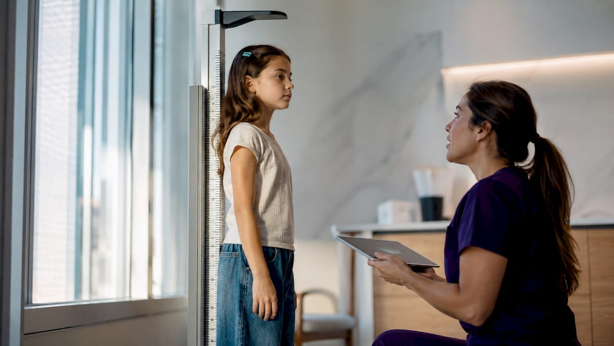 Girl having height measured during puberty checkup