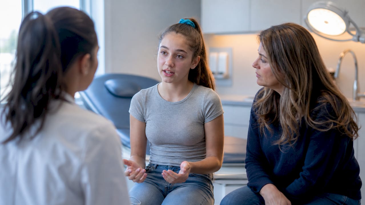 Teen discussing menstrual symptoms with clinician